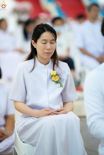 หญิงสาวสวมชุดขาวนั่งหลับตาทำสมาธิอย่างสงบในงานพิธี