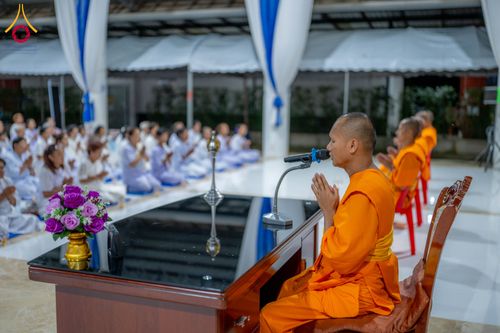 พระภิกษุสงฆ์กำลังเทศนาธรรมให้แก่ผู้เข้าร่วมโครงการอบรมที่นั่งฟังอยู่ด้านหลัง
