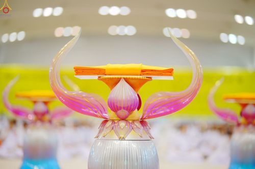 พานวางผ้าไตรจีวรสีเหลืองทองบนฐานรูปดอกบัวสีชมพูเงินตั้งอยู่ภายในอาคาร