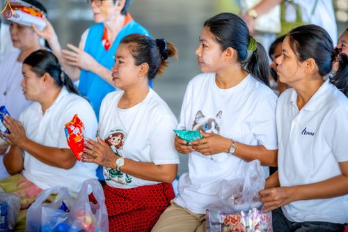 กลุ่มหญิงสาวสวมเสื้อสีขาวถือถุงอาหารแห้งเตรียมร่วมพิธีตักบาตร