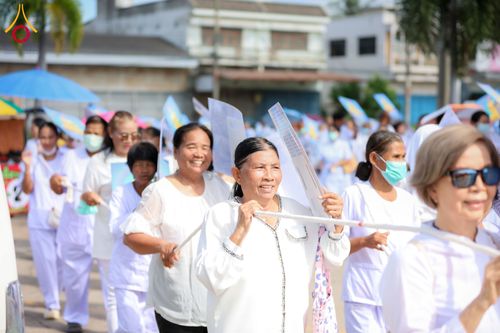 กลุ่มคนสวมชุดสีขาวเดินเรียงแถวถือเชือกและป้ายในขบวนพิธีทางศาสนา