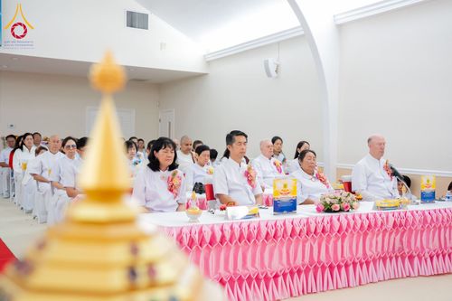 กลุ่มพุทธศาสนิกชนสวมชุดสีขาวนั่งพนมมือสำรวมจิตใจภายในอาคาร