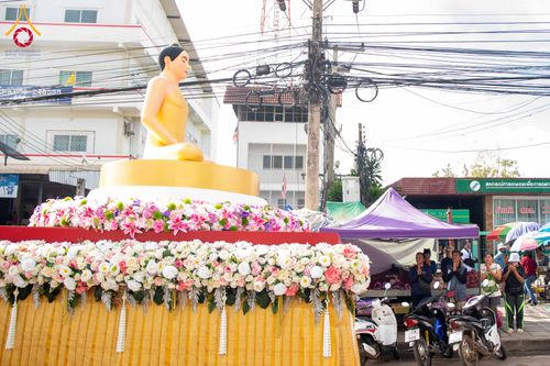 พระพุทธรูปสีทองบนรถบุษบกประดับดอกไม้สดในขบวนแห่กลางแจ้ง