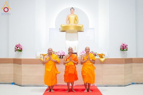 พระภิกษุสงฆ์ 3 รูปยืนพนมมืออยู่หน้าองค์พระพุทธรูปสีทองภายในอาคาร