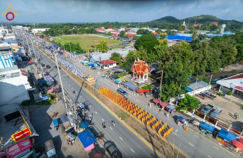 ขบวนพระภิกษุสงฆ์เดินแถวบนถนนท่ามกลางชุมชนและพุทธศาสนิกชนที่เดินตาม