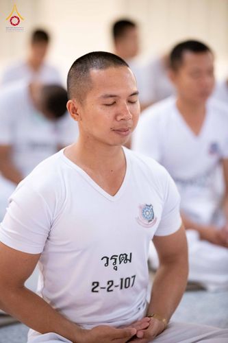 นักเรียนนายสิบตำรวจชายผมสั้นสวมเสื้อยืดสีขาวกำลังนั่งสมาธิหลับตาด้วยความสงบ