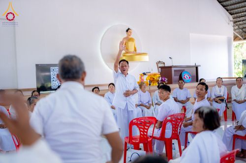 กลุ่มผู้เข้าร่วมโครงการอบรมในชุดสีขาวนั่งฟังวิทยากรบรรยายภายในอาคารปฏิบัติธรรม