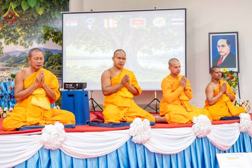 พระสงฆ์ 4 รูปนั่งพนมมือบนเวทีในพิธีกรรมทางศาสนา