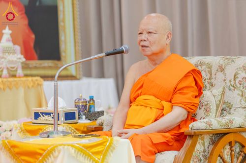 พระภิกษุสงฆ์ครองจีวรสีส้มกำลังนั่งพูดผ่านไมโครโฟนในงานสัมมนา
