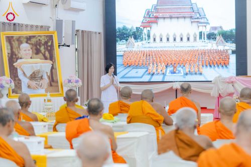 ผู้หญิงชุดขาวกำลังบรรยายในงานสัมมนาที่มีพระภิกษุสงฆ์เข้าร่วมรับฟัง