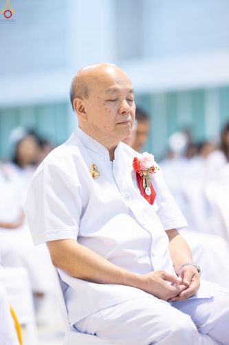 ชายสูงวัยสวมชุดขาวนั่งหลับตาทำสมาธิในพิธีทางศาสนา