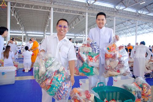 ชายสองคนถือถุงข้าวสารอาหารแห้งในพิธีตักบาตรภายในอาคาร