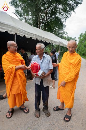 พระสงฆ์สองรูปกำลังส่งมอบสิ่งของช่วยเหลือให้แก่ชายสูงวัยในพื้นที่ประสบภัย