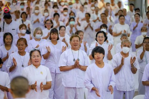 กลุ่มคนสวมชุดขาวพนมมือปฏิบัติธรรมในอาคาร