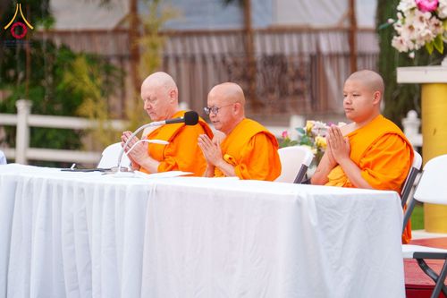 พระภิกษุสงฆ์ 3 รูปนั่งพนมมืออยู่หลังโต๊ะสีขาวในกิจกรรมทางศาสนา