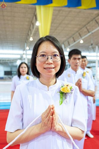 หญิงสวมชุดขาวพนมมือถือสายสิญจน์ในพิธีทางศาสนา