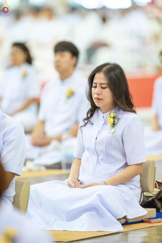 หญิงสาวสวมชุดสีขาวนั่งสมาธิในพิธีทางศาสนา
