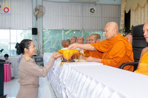 พระภิกษุสงฆ์กำลังประกอบพิธีบรรจุพระบรมสารีริกธาตุลงในพานทอง โดยมีเจ้าหน้าที่หญิงในชุดเครื่องแบบยืนรับด้วยความเคารพ