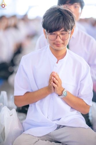 ชายหนุ่มสวมชุดขาวพนมมือไหว้ด้วยความสงบในพิธีทางศาสนา