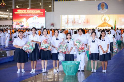 กลุ่มนักเรียนหญิงและชายถือถุงใส่ของแห้งเตรียมตักบาตรภายในสภาธรรมกายสากล