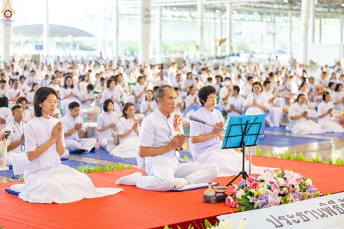 พุทธศาสนิกชนสวมชุดขาวนั่งพนมมือร่วมพิธีตักบาตรภายในอาคารสภาธรรมกายสากล