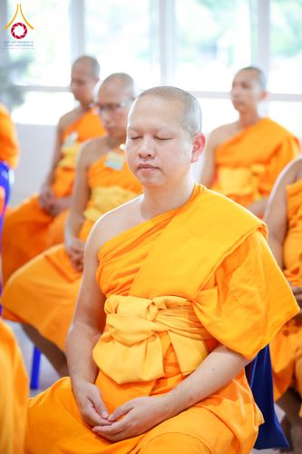 พระภิกษุสงฆ์หลายรูปนั่งสมาธิเรียงกันภายในอาคาร
