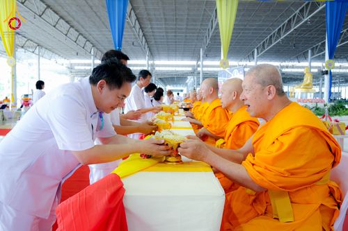 ชายสวมชุดขาวถวายพานดอกไม้แด่พระภิกษุสงฆ์ในพิธีทางศาสนา