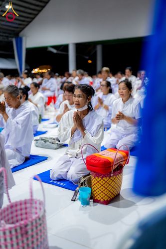 กลุ่มอุบาสิกาแก้วสวมชุดขาวนั่งพนมมือปฏิบัติธรรมภายในอาคาร