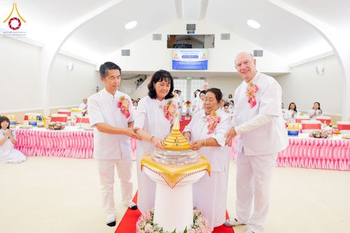 กลุ่มบุคคลสวมชุดสีขาวกำลังทำพิธีอัญเชิญพระบรมสารีริกธาตุภายในอาคาร