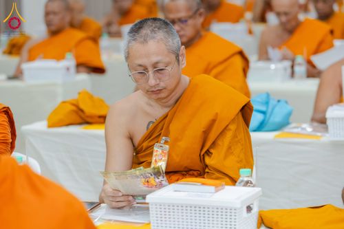พระภิกษุในจีวรสีส้มกำลังอ่านเอกสารอย่างตั้งใจในงานสัมมนา