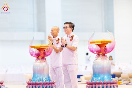 ชายสองคนสวมชุดสีขาวพนมมือในพิธีทอดผ้าป่าสมทบกฐิน โดยมีพานวางผ้าไตรตั้งอยู่ด้านหน้า