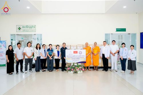 กลุ่มบุคคลยืนเรียงแถวหน้าป้ายโครงการบริจาคยาและเวชภัณฑ์ภายในอาคารศูนย์การแพทย์บุญรักษา