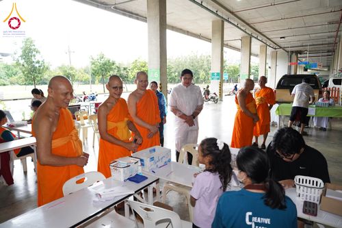 พระสงฆ์และเจ้าหน้าที่กำลังพูดคุยกับประชาชนที่จุดบริการภายในอาคารจอดรถ
