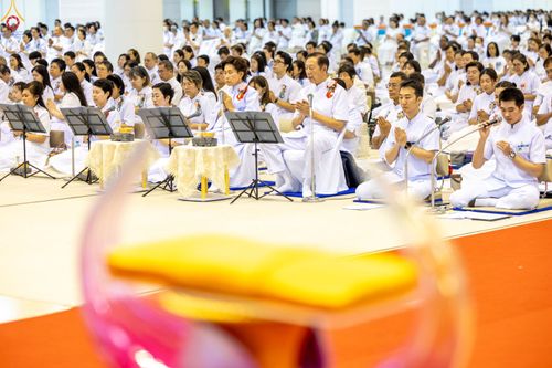 พุทธศาสนิกชนสวมชุดขาวนั่งพนมมือปฏิบัติธรรมภายในอาคารสภาธรรมกายสากล