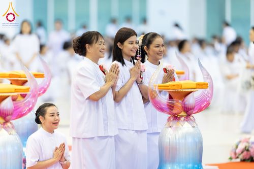 กลุ่มพุทธศาสนิกชนหญิงสวมชุดขาวพนมมือร่วมพิธีทอดผ้าป่าภายในอาคารสภาธรรมกายสากล