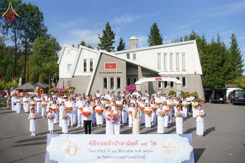 กลุ่มคนจำนวนมากสวมชุดสีขาวถ่ายภาพร่วมกันหน้าอาคารวัดพระธรรมกายนอร์เวย์ในวันจัดงานพิธีทอดผ้าป่าสามัคคี