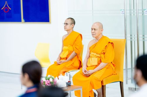 พระภิกษุสงฆ์สองรูปนั่งอยู่บนเก้าอี้ภายในอาคารเพื่อประกอบพิธีการ