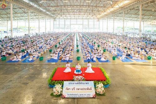 พุทธศาสนิกชนสวมชุดขาวนั่งร่วมพิธีตักบาตรข้าวสารอาหารแห้งภายในสภาธรรมกายสากล
