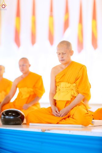 พระภิกษุสงฆ์ห่มจีวรสีเหลืองนั่งสมาธิหลับตาอย่างสงบภายในอาคาร