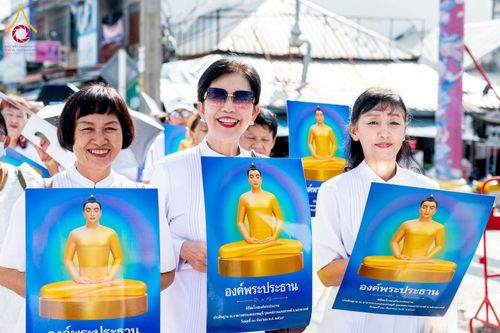 กลุ่มพุทธศาสนิกชนหญิงสวมชุดสีขาวถือป้ายภาพองค์พระประธานในงานพิธีทางศาสนา