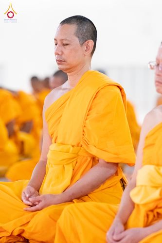 พระภิกษุสงฆ์ห่มจีวรสีเหลืองทองกำลังนั่งหลับตาทำสมาธิอย่างสงบ