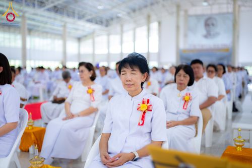 กลุ่มคนสวมชุดขาวนั่งหลับตาทำสมาธิในพิธีทางศาสนาภายในอาคาร