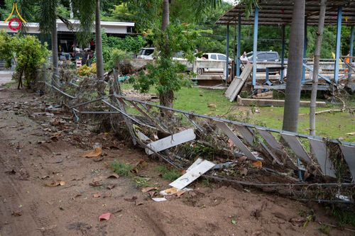 รั้วเหล็กที่พังเสียหายและเศษดินโคลนบนพื้นดินหลังเหตุการณ์น้ำท่วม