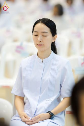หญิงสาวสวมชุดสีขาวนั่งหลับตาทำสมาธิอย่างสงบ