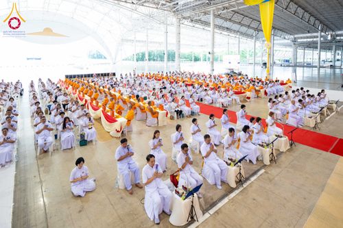 กลุ่มพุทธศาสนิกชนในชุดขาวและพระภิกษุสงฆ์กำลังประกอบพิธีทางศาสนาภายในอาคารสภาธรรมกายสากล