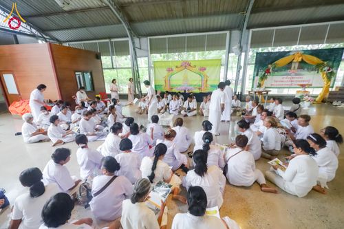 กลุ่มคนสวมชุดขาวนั่งล้อมวงทำกิจกรรมภายในอาคาร