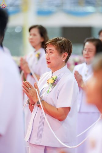 หญิงวัยกลางคนสวมชุดสีขาวพนมมือในพิธีทางศาสนา