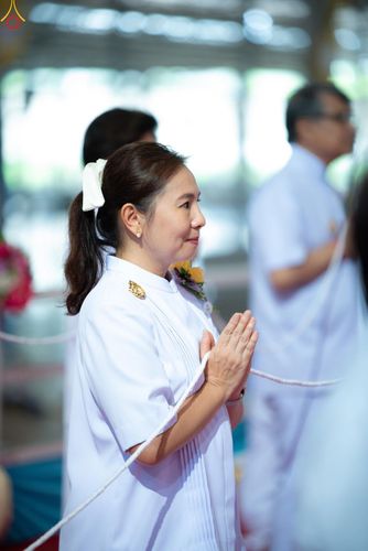 หญิงสาวสวมชุดสีขาวกำลังพนมมือด้วยความสงบในพิธีทางศาสนา