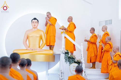 พระสงฆ์หลายรูปกำลังประกอบพิธีทางศาสนาหน้าพระพุทธรูปสีทององค์ใหญ่ภายในวัด