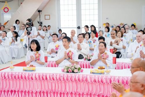 กลุ่มคนสวมชุดสีขาวนั่งพนมมือร่วมพิธีทางศาสนาภายในอาคาร